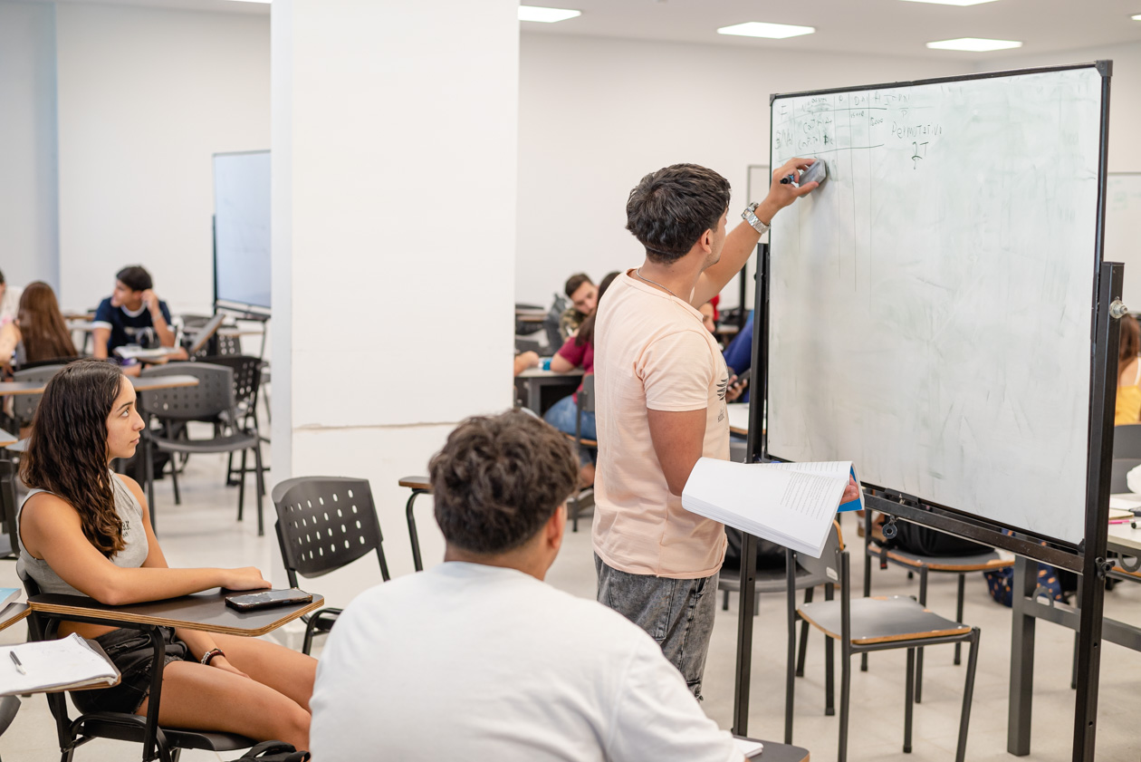 estudiantes mirando y escribiendo sobre pizarra blanca 