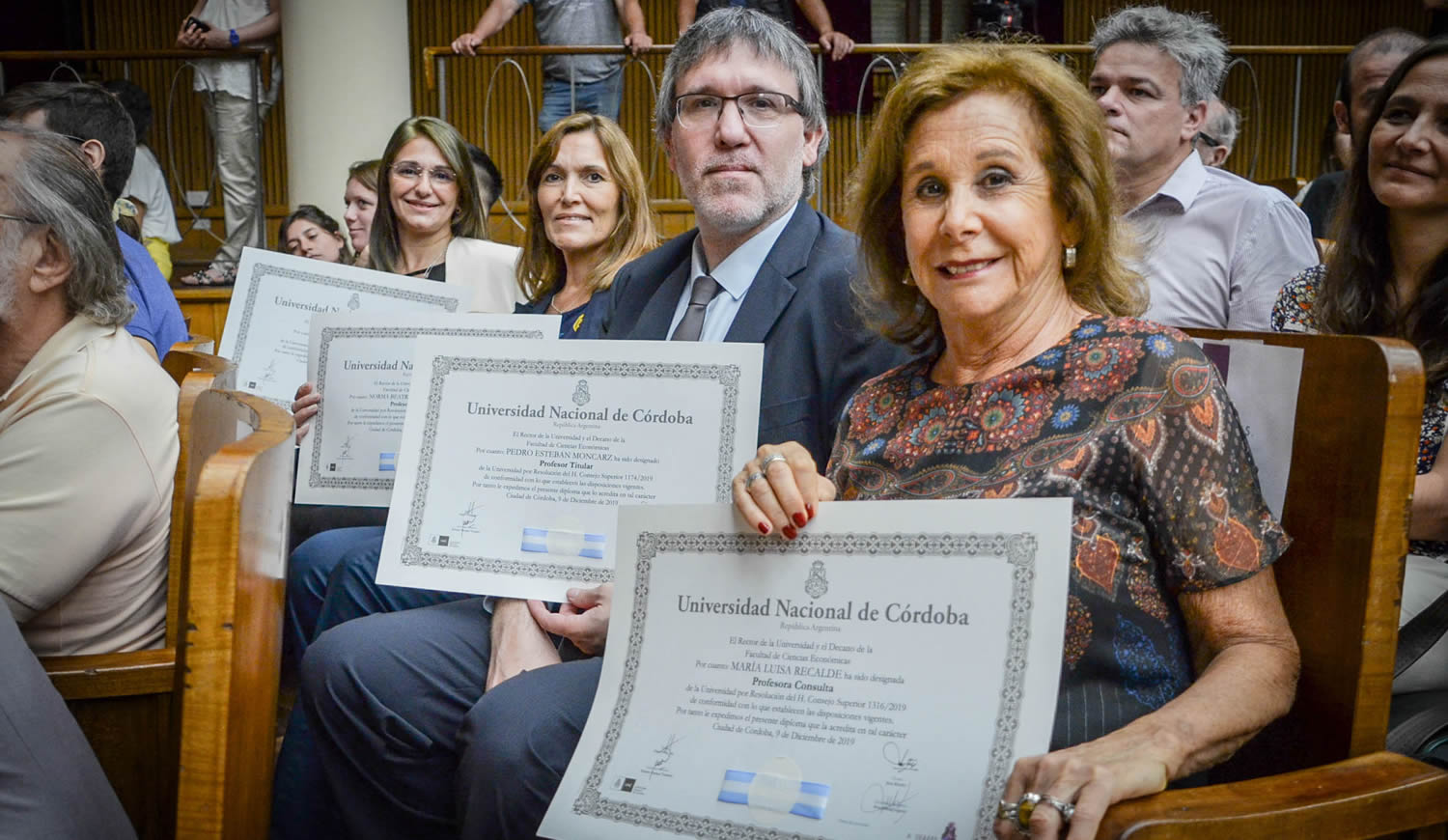 Los profesores Leila Andalle, Norma Bertoldi, Pedro Moncarz y María Luisa Recalde muestran sus diplomas sentados en el Salón de Actos del Pabellón Argentina