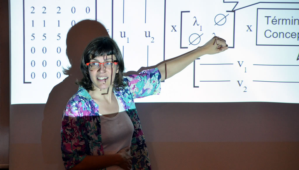 Imagen de la profesora Laura Alonso junto a la pizarra señalando unas ecuaciones