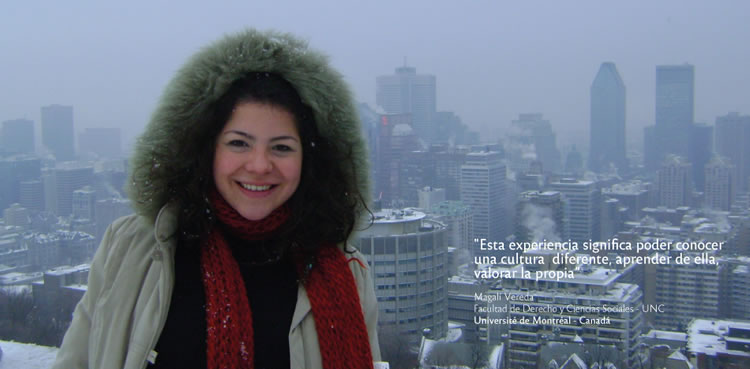 Una mujer sonriendo usando una campera grande con capucha y piel en medio de un paisaje nevado