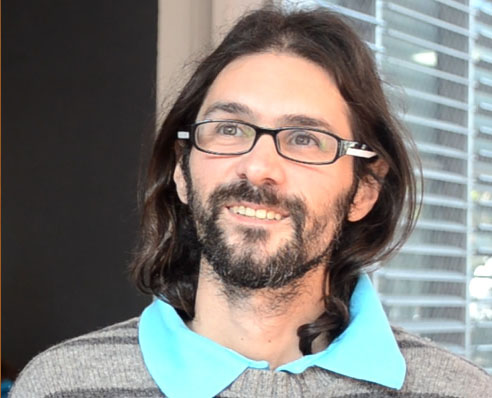 Hernán Morero sonriendo con anteojos en un día soleado y mirando hacia un costado