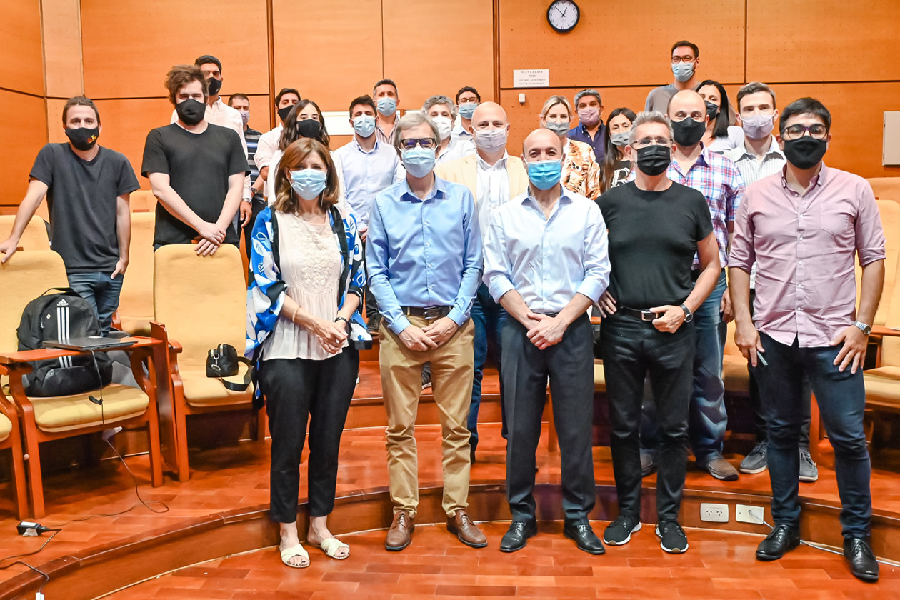 Una treintena de participantes del evento de presentación, de pie y con barbijos, en uno de los auditorios de la Escuela de Graduados