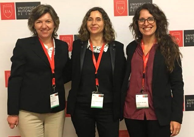 Mónica Buraschi, Florencia Peretti y Celina Amato sonrientes de pie con tiras porta identificación que cuelgan de su cuello en el marco de un congreso