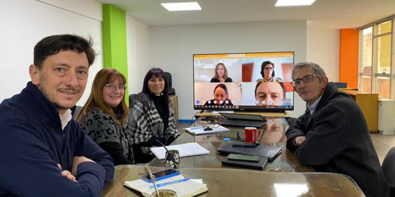 Pancho Marchiaro, dos funcionarias, una pantalla gigante y el profesor Enrique Bianchi, sentados