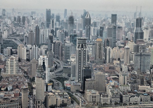 Una ciudad desde el aire con una treintena de edificios altos en un día soleado y con una leve nube de smog