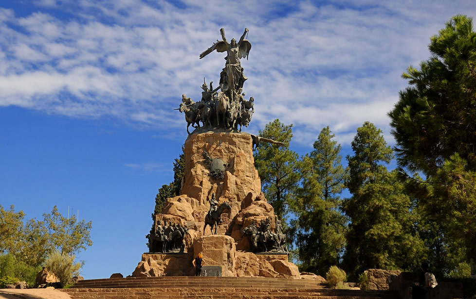 Cerro de la Gloria en un día soleado con algunas nubes y hay cinco árboles detrás