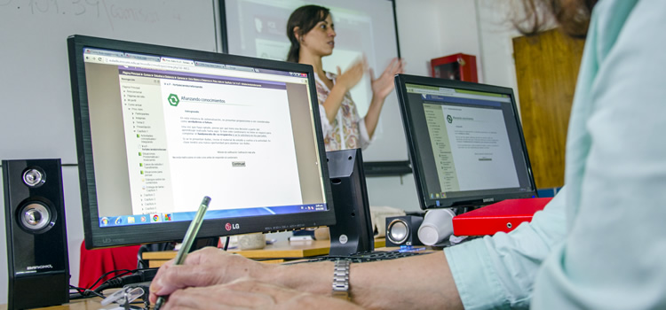 Una docente frente a unos estudiantes en computadoras