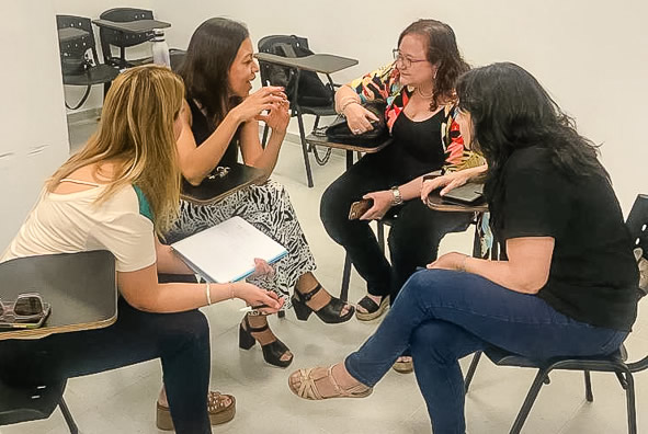Cuatro docentes mujeres sentadas en una ronda sobre sillas conversando