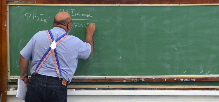 Un docente escribiendo en un pizarrón