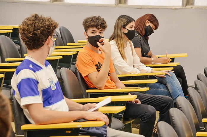 Dos estudiantes mujeres y dos estudiantes varones sentados en una aula, distanciados