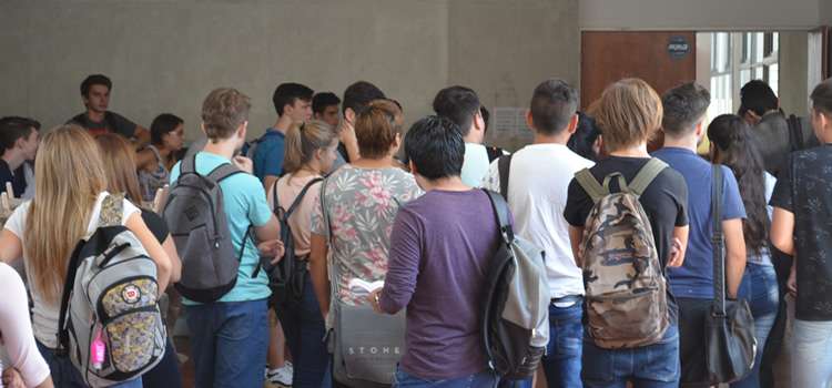 Una decena de estudiantes de espaldas a punto de ingresar a un aula de la Facultad de Ciencias Económicas