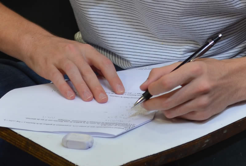 Un estudiante escribe con un portaminas sobre un papel junto a una goma de borrar