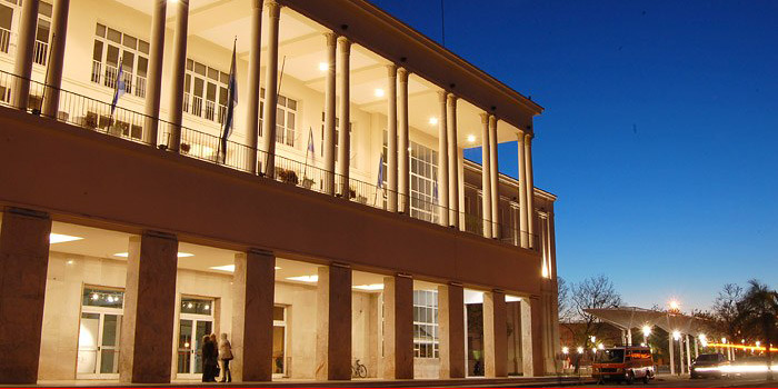 Edificio del Pabellón Argentina con iluminación en sus galerías en un atardecer con cielo despejado